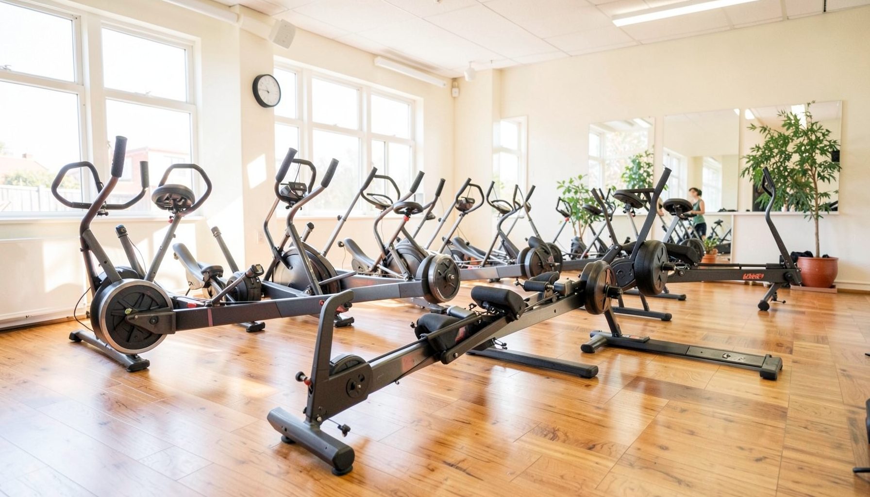 Bright, airy indoor rowing studio with warm wood floors, rowing machines lined up in soft natural light, and an energetic yet welcoming atmosphere